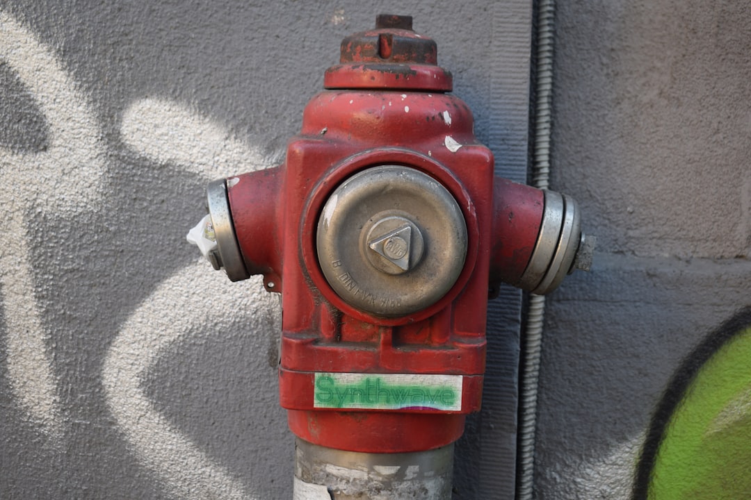 A red fire hydrant sitting next to a wall