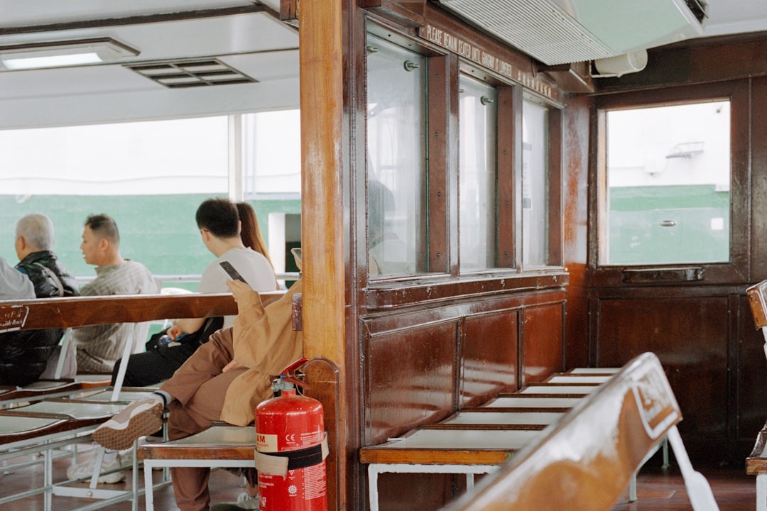 People sitting inside a wooden ferry with windows.